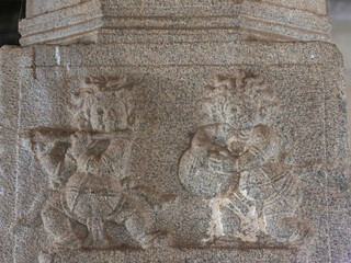 Hampi, Karnataka, India - November 5, 2013: Vijaya Vitthala Temple. Closeup of gray stone fresco at bottom of pillar in mandapam showing 2 musicians, one with flute, one with drum.