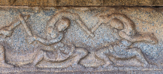 Hampi, Karnataka, India - November 5, 2013: Vijaya Vitthala Temple. Closeup of brown stone fresco depicting women performing sword dance.