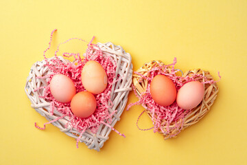 Decorative nest with colorful Easter eggs on yellow background
