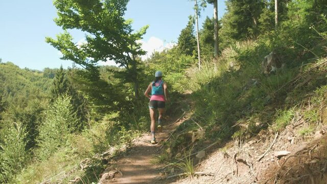 Beautiful forest trail run shot in slow motion. Young athlete woman running uphill, jogging, exploring. 