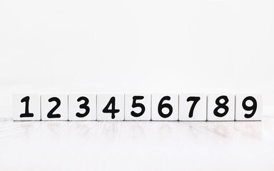 Ascending order numbers, black typeface on white cube with reflection on wood table surface. Finance, strategy economy, education concept, set of permute number on white background with copy space.
