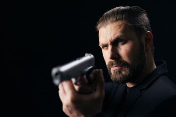 Bearded gangster in suit threatening with gun over black studio background. Confident bandit aiming with weapon. Armed person.