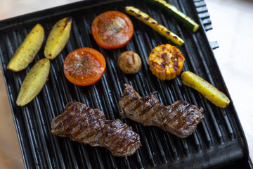 Electric grill with roast beef, spicy potatoes, mushrooms and vegetables