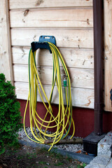Yellow and green striped garden hose hung on a hook. Spala Poland