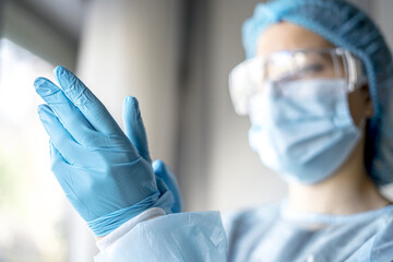 Female doctor putting on protective blue gloves