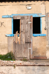 Dilapidated building with empty blue framed window and partial door frame leaning against it. Rzeczyca Poland
