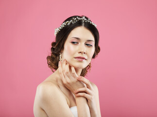 Fashionable bride with gorgeous diadem. Studio portrait over pink background. Beautiful model with bridal makeup and hairstyle.