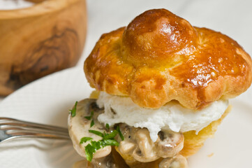 Egg and mushroom in brioche on white plate with a fork