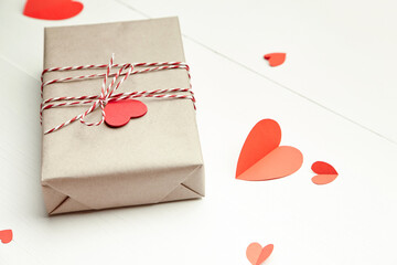 Valentines day gift box decorated with red hearts on white wooden background