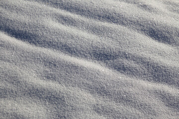 Fresh white snow sparkling in the sun with highlights and shadows for background