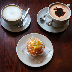 Hot cappuccino and latte coffee and muffin on a table.