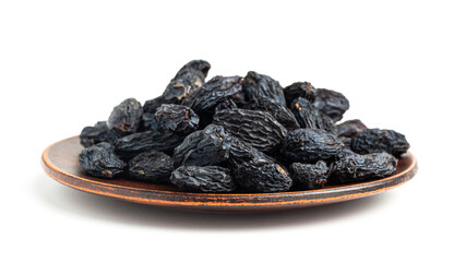 Dark blue raisins on a plate isolated on white background