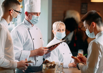 Cafe staff on morning briefing wearing protective masks.