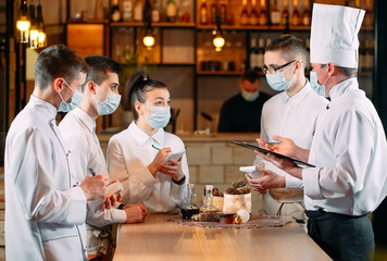 Fototapeta na wymiar Cafe staff on morning briefing wearing protective masks.