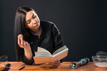 Beautiful female looking for macaroon recipe in the cook book.