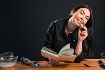 Beautiful female looking for macaroon recipe in the cook book.