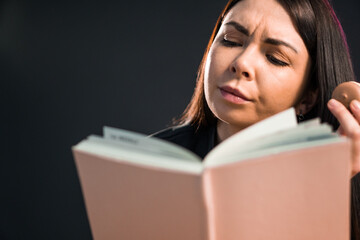 Young woman reading book while tasting a macaroon.