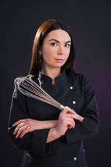 Young woman holding a whisk ready to cook some sweets.