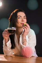 Portrait of young woman with cup of coffee and macaroon over black background.