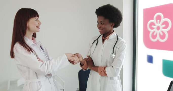 Medical Handshake. Doctoral Meeting. Two Confident Doctor Standing In Hospital And Shake Their Hands. Shot Of Two Medical Workers In Lab Coats Shaking Hands. Teamwork, Partnership, Trust Concept