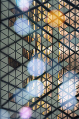 Modern glass wall from small triangles and bokeh lights on the forefront.