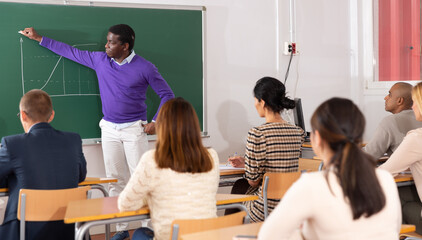 Portrait of african american professor lecturing to attentive adult students at university...