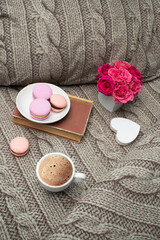 Breakfast for Valentine's day. Cup of coffee and gift box with roses flowers in the shape of heart with sweet macaroons on bed.