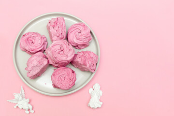 Sweet marshmallow on plate and cupid angel decorations, Valentines Day concept on pink background with copy space