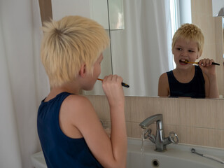 Two school brothers brush their teeth in bathroom. Twin children have good time together doing hygiene