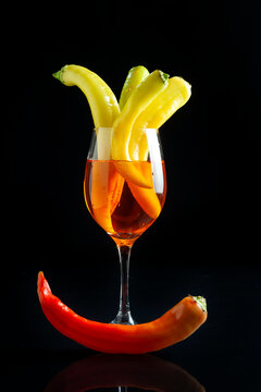 green chili peppers and red peppers, inside a wine glass with cruet and red vinegar