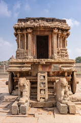 Hampi, Karnataka, India - November 5, 2013: Vijaya Vitthala Temple. Closeup of brown stone chariot from the front under blue cloudscape. Elephants in front. 