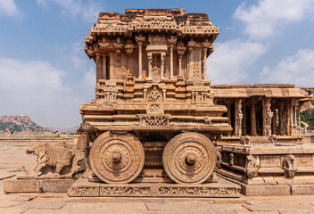 Hampi, Karnataka, India - November 5, 2013: Vijaya Vitthala Temple. brown stone chariot closeup under blue cloudscape. 