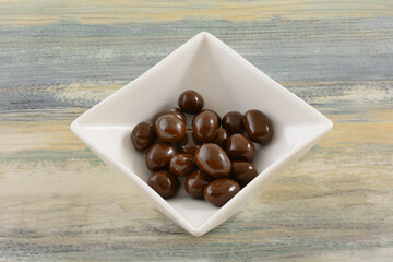 Chocolate covered peanuts candy in white candy dish on table