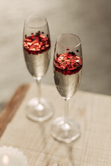 Happy Valentines day celebration concept. Close up of 2 two glasses with sparkling champagne and red heart shaped confetti. Love potion in glass