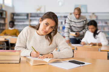 Obraz premium Portrait of young adult woman studying in at public library