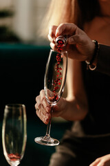 Happy Valentines day celebration concept. Man pouring love potion in woman's empty champagne glass. Red Heart shaped confetti in glass. Close up