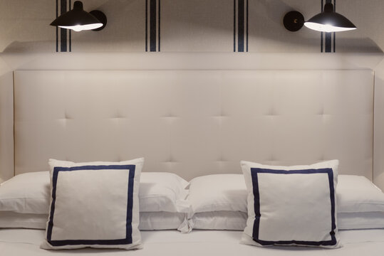 Habitaci&oacute;n con dos focos de luz arriba y varios cojines blancos con una decoraci&oacute;n minimalista. 