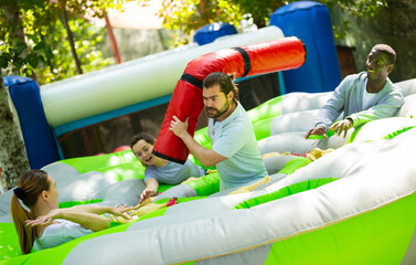 Fototapeta na wymiar Funny friends playing on an inflatable trampoline in an amusement park. High quality photo