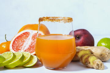 Closeup of a glass of fruit juice. Fresh fruit: grapefruit, apple, mandarin, lime. Spices to strengthen the body: fresh ginger, cinnamon. Healthy lifestyle.