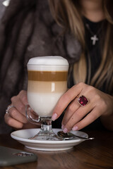 Glamorous girl in a fur coat drinks her coffee, latte, cappuccino