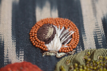 Couture embroidery of persimmon on ikat fabric. Still life with fruits