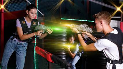 Fototapeta na wymiar Girl with laser guns took aim and having fun with friends during laser tag game