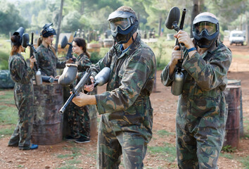 Fototapeta premium Two vigorous paintball players in full gear having fun before game outdoors