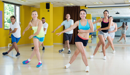 Fototapeta na wymiar Group of smiling active women and men dancing in modern dancing school. .