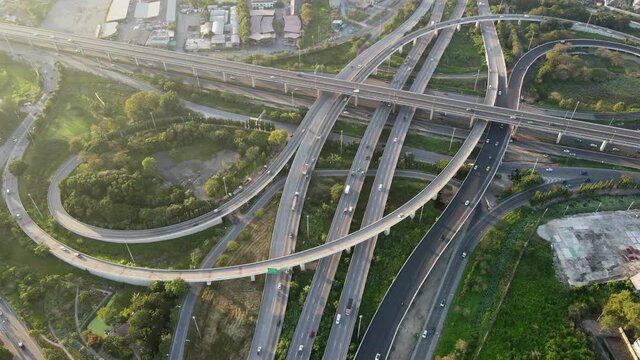 4K. Aerial view of road interchange or highway intersection with busy urban traffic speeding on the road. Junction network of transportation taken by drone.