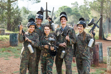 Portrait of smiling team of paintball players with marker guns ready for game outdoors