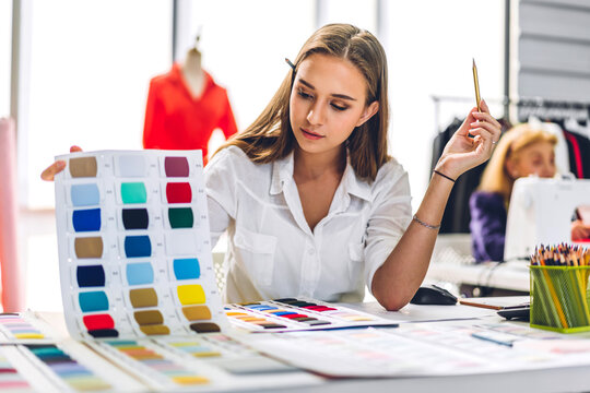 Portrait of young beautiful pretty woman fashion designer stylish sitting and working.Attractive young girl use desktop conputer and colorful fabrics at fashion design studio - Powered by Adobe