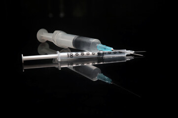 syringe and needle - on larger syringe lying on top of a smaller one