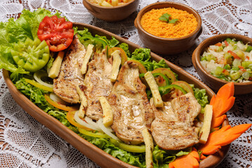 Sliced ​​chicken breast, grilled with rennet cheese and green salad served in clay bowl. Traditional Brazilian cuisine.