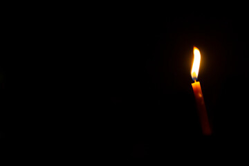 light candle in the darkness on the black background.